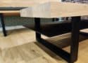 Unieke salontafel met dik eiken tafelblad en een zwart stalen onderstel met staalplaat als opbergruimte en ligplank